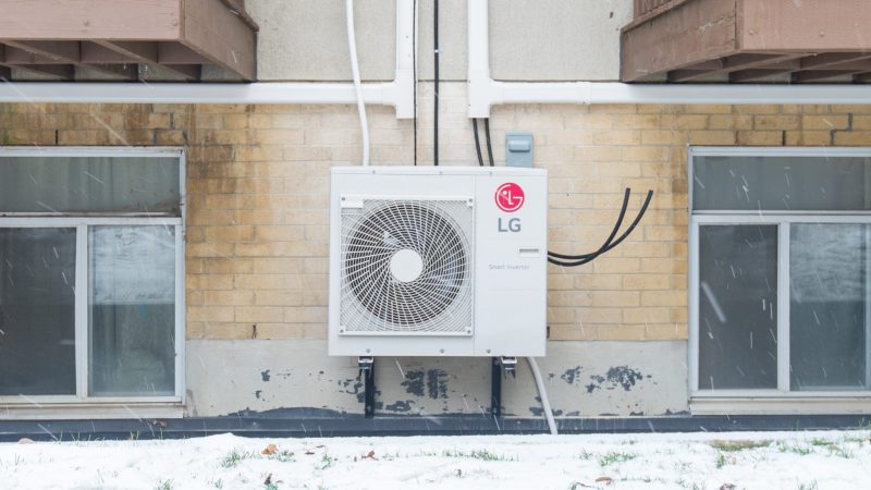 A heat pump outside a rental building in winter.