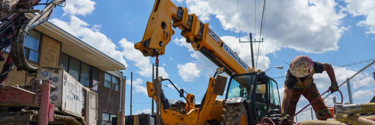 A construction site with a worker in the foreground and machinery in the background.