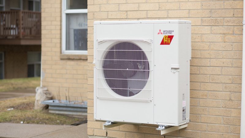 A Mitsubishi heat pump is installed on a pale brick wall