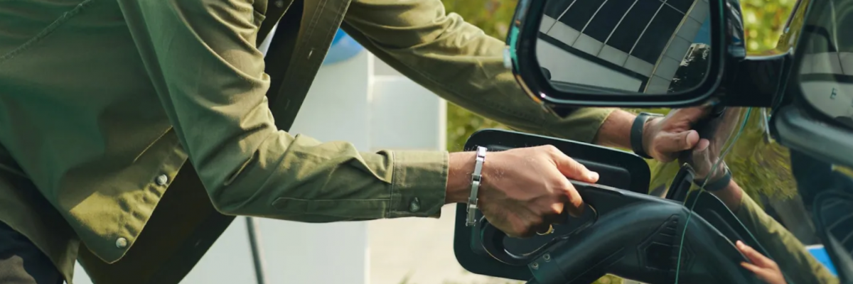 A person plugs in their EV for a charge.