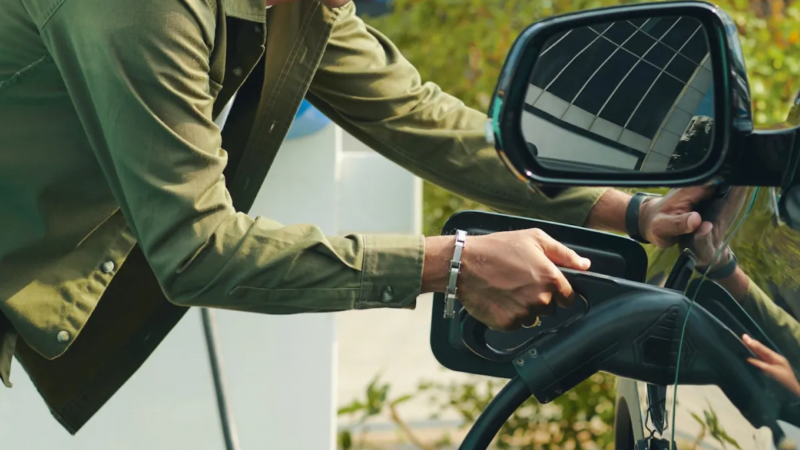 A person plugs in their EV for a charge.