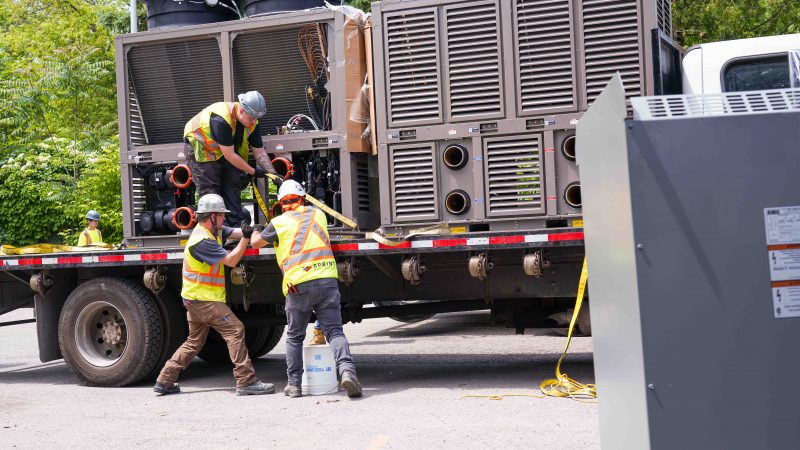 Construction workers are unloading a new HVAC system for a deep retrofit.